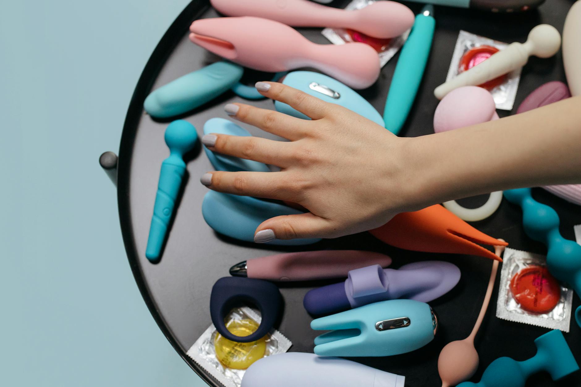 Woman thoughtfully holding blue and pink silicone vibrators to understand intensity options