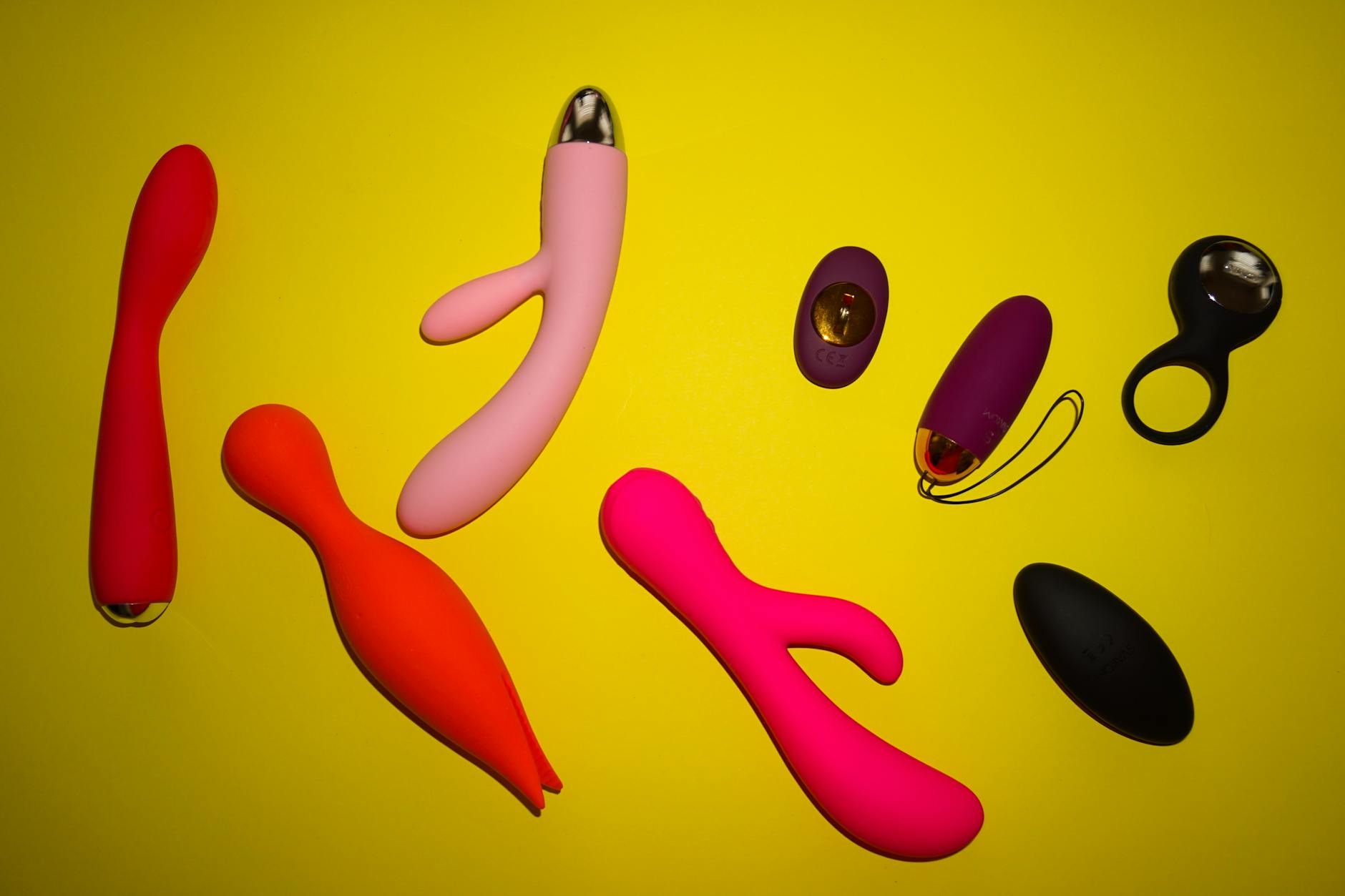 Collection of colorful vibrators and personal pleasure devices displayed on a bright yellow background