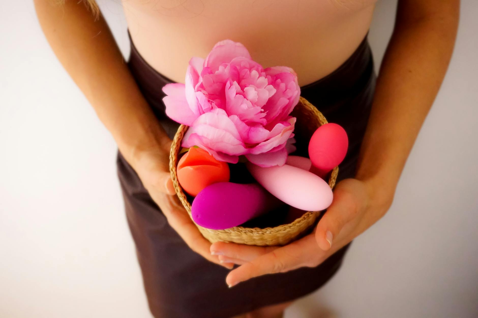 A collection of colorful vibrators and intimate wellness products displayed with fresh flowers, showcasing options for sensitive users.